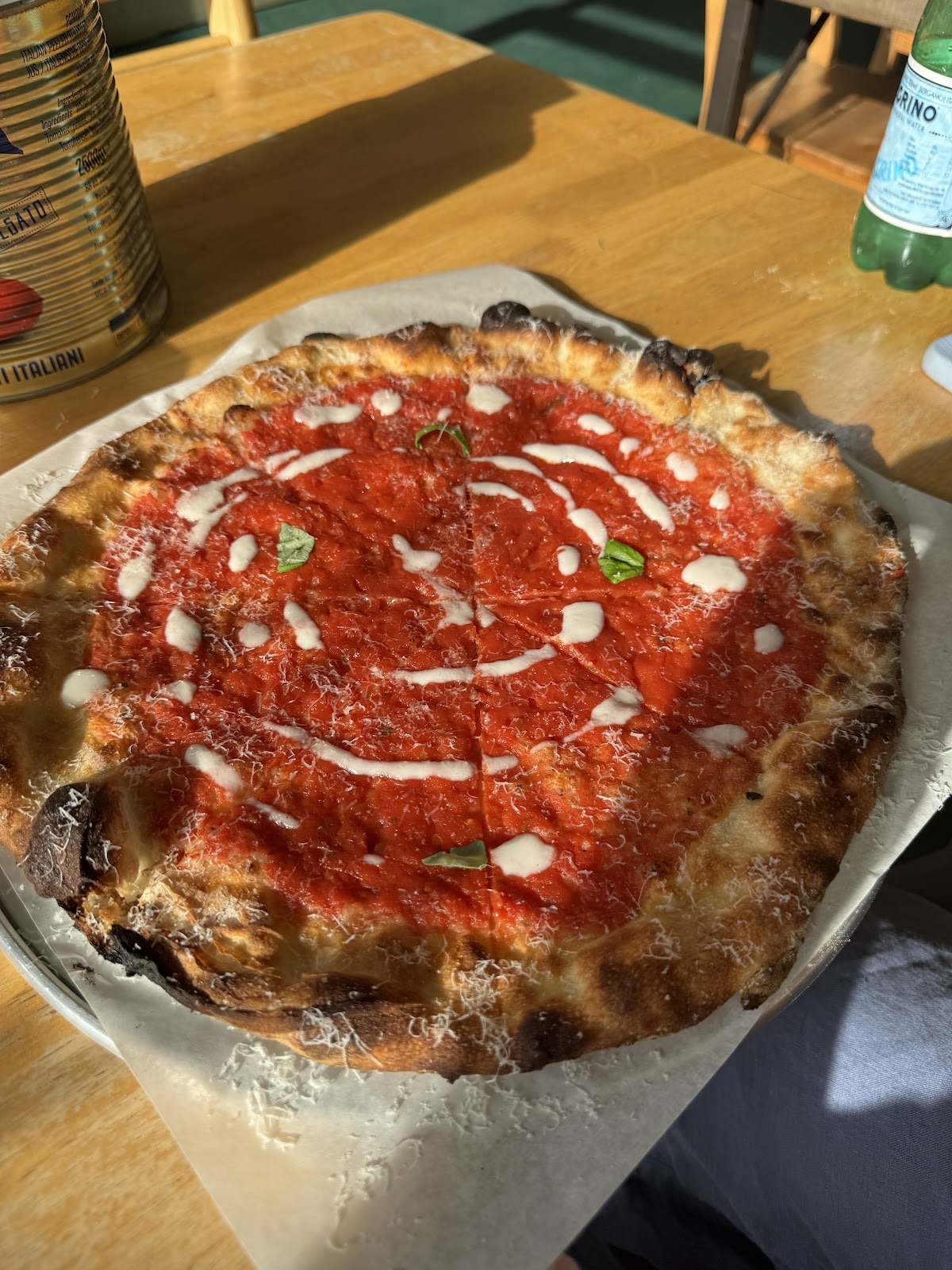 A red marinara-style pizza drizzled with cream and topped with basil